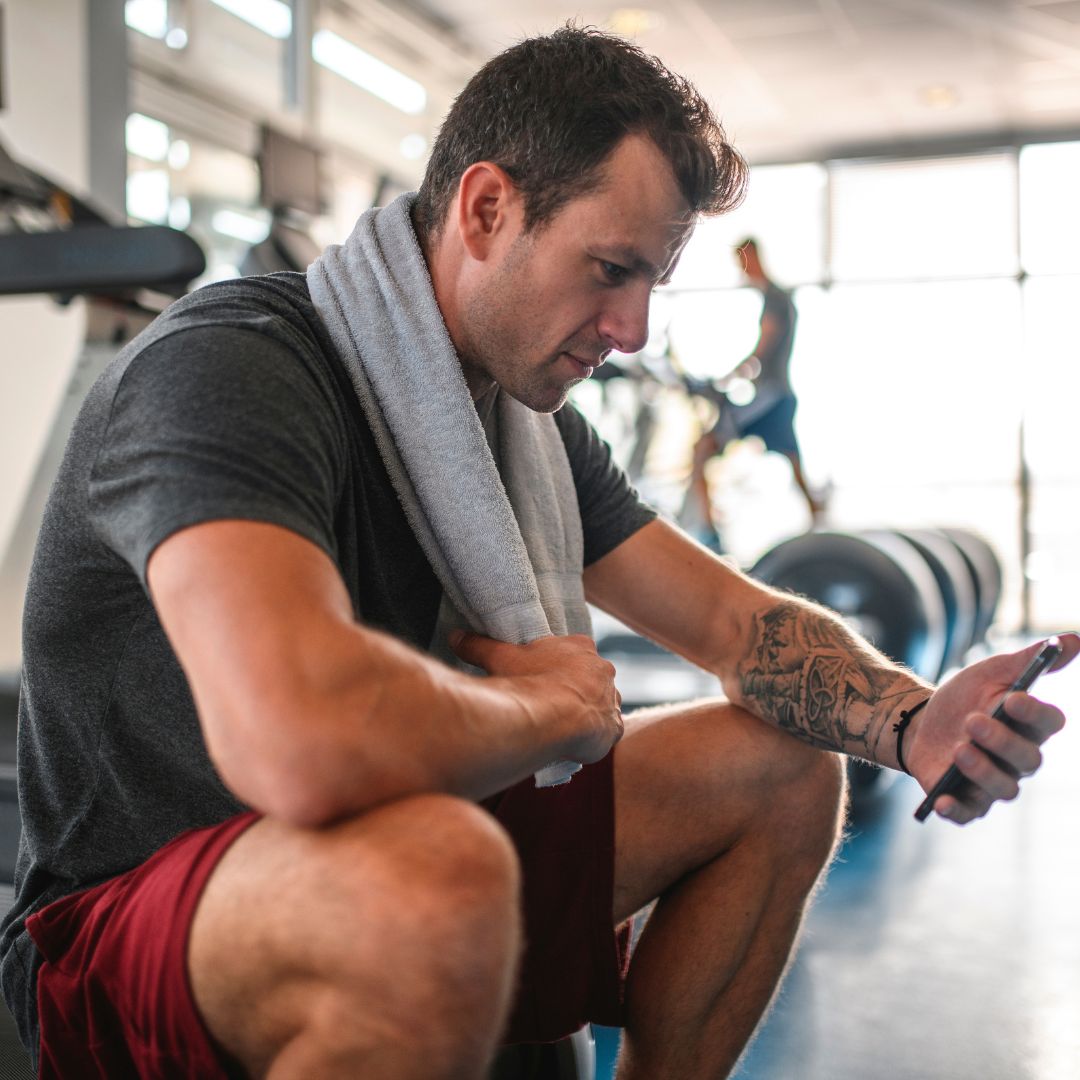 guy sitting at the gym looking at his phone