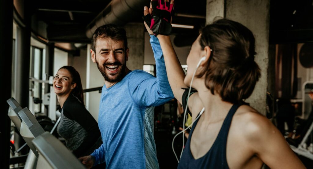 Two people high five on treadmills
