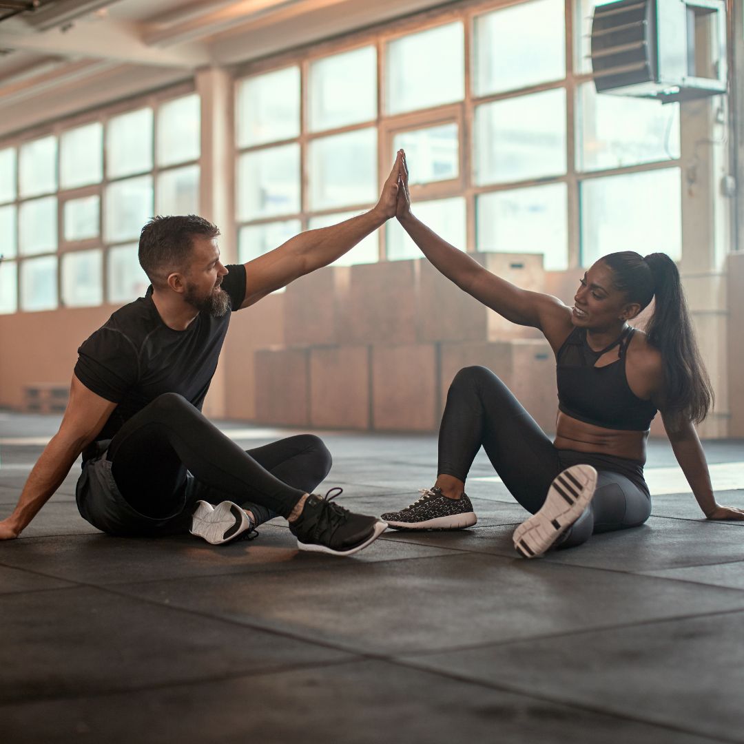 Two people high five while at the gym